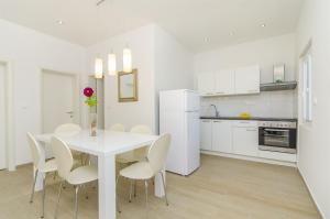 eine weiße Küche mit einem weißen Tisch und Stühlen in der Unterkunft House Franka in Vinišće