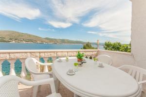 een witte tafel en stoelen op een balkon met uitzicht op het water bij Apartments Natasa in Trogir