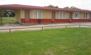 a small yellow and red house with a grass yard at Relax Inn Ranger in Ranger