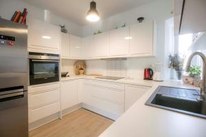 una cocina blanca con armarios blancos y fregadero en Season4All Apartments, en Mali Lošinj