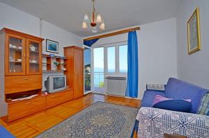 ein Wohnzimmer mit einem blauen Sofa und einem TV in der Unterkunft Apartment Ksenija in Drvenik