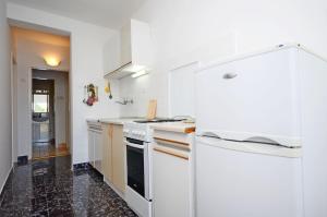eine weiße Küche mit einem Herd und einem Kühlschrank in der Unterkunft Apartment Ksenija in Drvenik