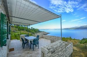a patio with a table and chairs and a view of the water at House Krunoslav in Postira