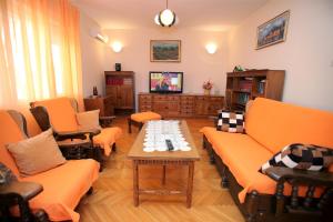 a living room with orange couches and a table at Apartment Baturina in Trogir