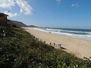 a beach with people walking on the sand and the ocean at Casa Praia Mole in Florianópolis