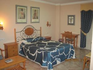 a bedroom with a bed, chair, table and a painting on the wall at Hotel Caballo Negro in Puerto Real
