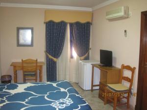 a bedroom with a bed and a desk and a television at Hotel Caballo Negro in Puerto Real