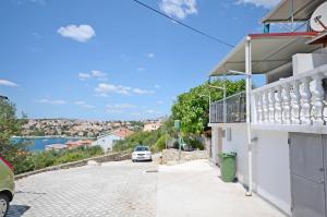 ein Haus mit Balkon und ein Auto, das auf einer Straße geparkt ist in der Unterkunft Apartments Petar in Trogir