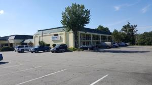 a parking lot with cars parked in front of a building at Red Carpet Inn Kinston in Kinston