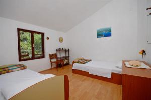 a bedroom with two beds and a table and a chair at Apartments Antun in Vrboska