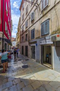 eine Gruppe von Menschen, die eine Straße mit Gebäuden entlang gehen in der Unterkunft Apartment and Room Old town in Split