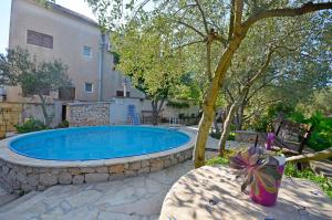 a swimming pool with a tree and a building at Apartment Gordan in Murter