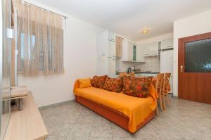 a living room with an orange couch and a kitchen at Apartments Branko in Postira