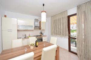 a kitchen with a wooden table and white cabinets at Apartment Gordan in Murter