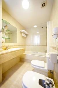 a bathroom with a toilet and a sink and a tub at Hotel Florida in Arteixo