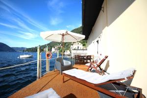 a boat with chairs and an umbrella on the water at Darsena di Riva Grande in Moltrasio