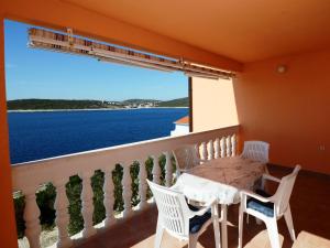 ein Balkon mit Tisch und Stühlen und einem großen Fenster in der Unterkunft Apartments Marijo in Sevid