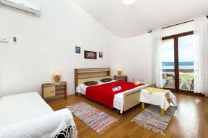 a white bedroom with a red bed and a window at Apartments Nevenka in Sumpetar