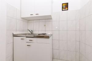 a white kitchen with a sink and white tiles at Apartments Nevenka in Sumpetar