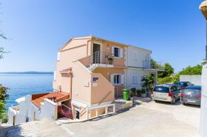 um edifício rosa com carros estacionados em frente em Apartments Nives em Trogir