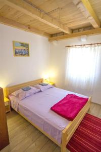 a bedroom with a large bed with a red blanket on it at Apartments Zeljko in Gdinj