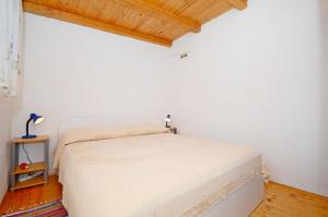 a white bed in a room with a wooden ceiling at House Mislav II in Velike Kuknjare