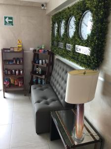 una sala de espera con sofá y relojes en la pared en Herbal Inn Suites, en Puebla