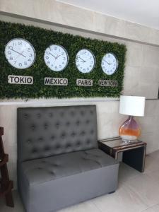 um quarto com relógios numa parede com um banco em Herbal Inn Suites em Puebla