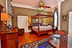 - une chambre avec un lit à baldaquin et un bureau dans l'établissement Southern Mansion, à Cape May