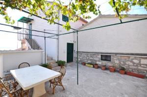 eine Terrasse mit einem Tisch und Stühlen sowie ein Gebäude in der Unterkunft Apartment Aljosa in Bol