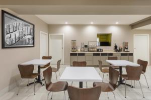 Super 8 by Wyndham Asheville Airport في فليتشر: غرفة طعام مع طاولات وكراسي ومطبخ