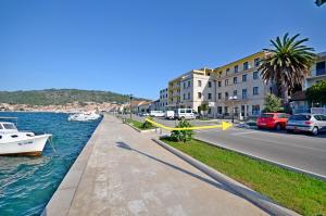 a street next to a river with a boat in the water at Apartment and Rooms Angela in Vela Luka