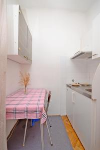 a small kitchen with a table with a pink table cloth at Apartment and Rooms Angela in Vela Luka