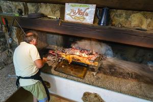 a man cooking food in an outdoor oven at Agriturismo Lu Nodu in Greuli 