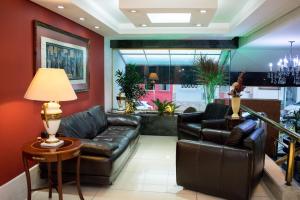 a living room with a leather couch and a table at Hotel Jacques Georges Business in Pelotas