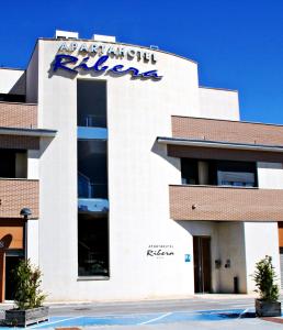 an apartment building with a sign on it at Apartahotel Ribera in Arroyo de la Encomienda