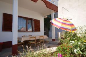 a patio with a table and a colorful umbrella at Comfort apartment on the beach in Kali
