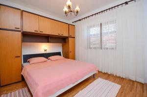 una camera con letto rosa e armadi in legno di Apartments Zvonimir a Senj