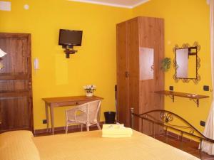 a yellow room with a bed and a table and a desk at Le Tre Caravelle in Trabia
