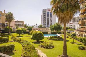 a park with a palm tree and a swimming pool at Apartment Erisa in Torremolinos