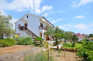 een wit huis met een trap en een tuin bij Apartments Ivanka in Krk