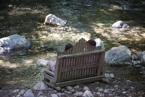 two people sitting on a bench next to a river at Big Sur River Inn in Big Sur