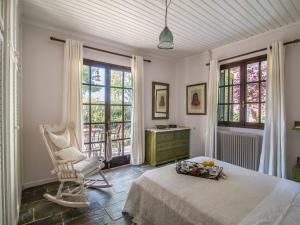 een slaapkamer met een bed, een stoel en ramen bij Mansion Domenica in Sarakinádhon