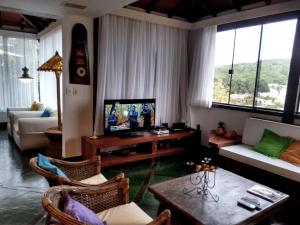 a living room with a couch and a tv in it at Casa Muito Aconchegante em Buzios in Búzios