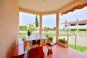 a porch with a table and a view of a yard at Apartments Bogetic in Premantura