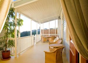 een veranda met stoelen, tafels en ramen bij McHardy Lodge in Napier
