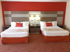 two beds in a hotel room with red walls at Hawthorn Suites Irving DFW South in Irving