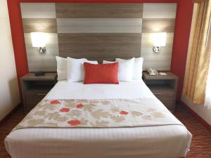 a hotel room with a large bed with a red pillow at Hawthorn Suites Irving DFW South in Irving
