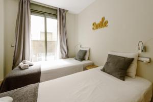 two beds in a room with a smile sign on the wall at 1E Azofaifo St Apartment in Seville