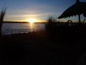 a sunset over a body of water with the sun setting at Uros Suyawi Titicaca Lodge in Puno